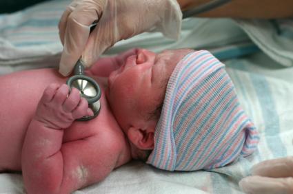 baby laying on back with doctor's stethoscope on chest