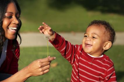mom and baby playing outdoors with a dandelion