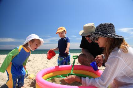 parents and toddlers wearing hats and playing on sandy beach