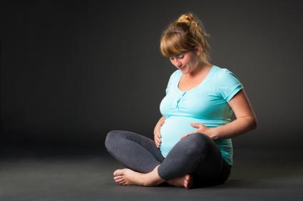 pregnant woman sitting cross-legged touching her belly