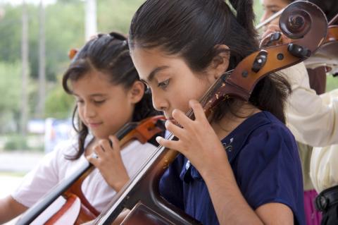 School-age girls playing cello in music class
