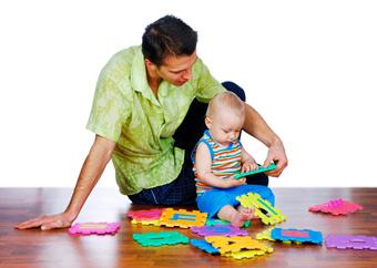 father and baby on floor playing with foam blocks